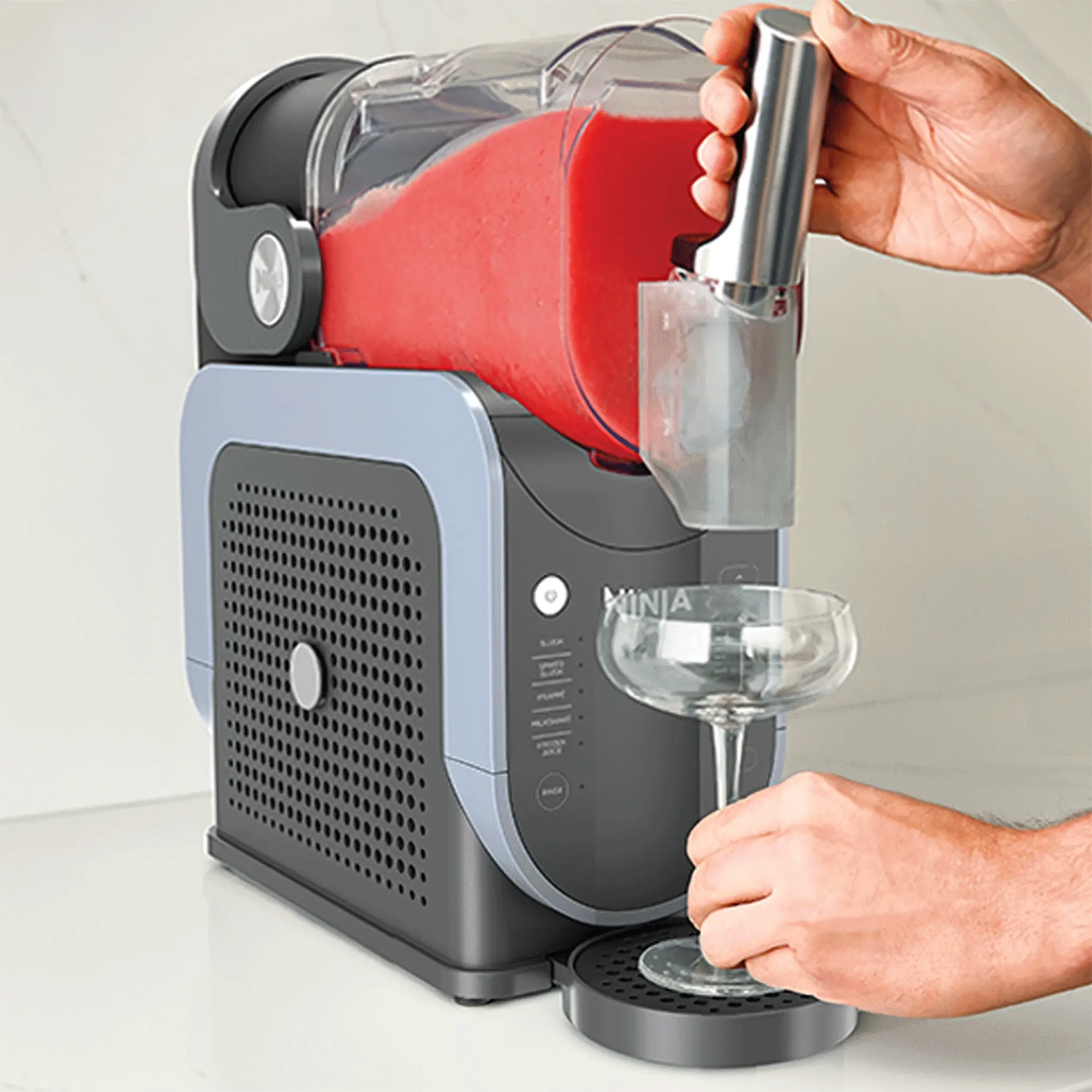 Person using the Ninja SLUSHi handle to dispense a red frozen drink